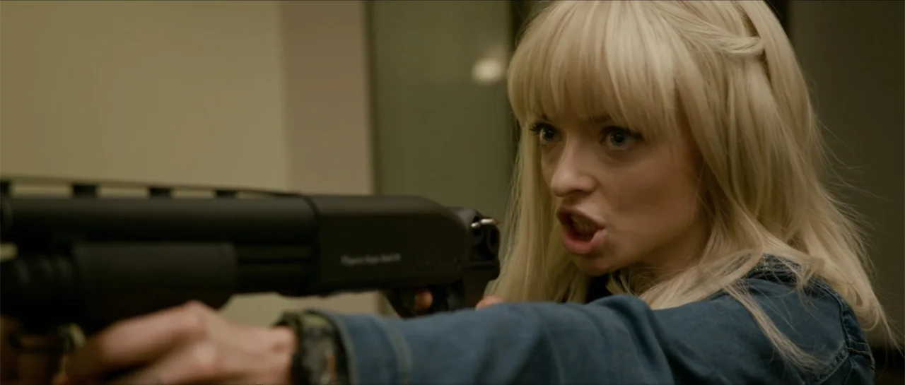 The Vault (2017) movie still: medium — An interior space with beige walls serves as the backdrop for the encounter. A young woman with blonde hair…