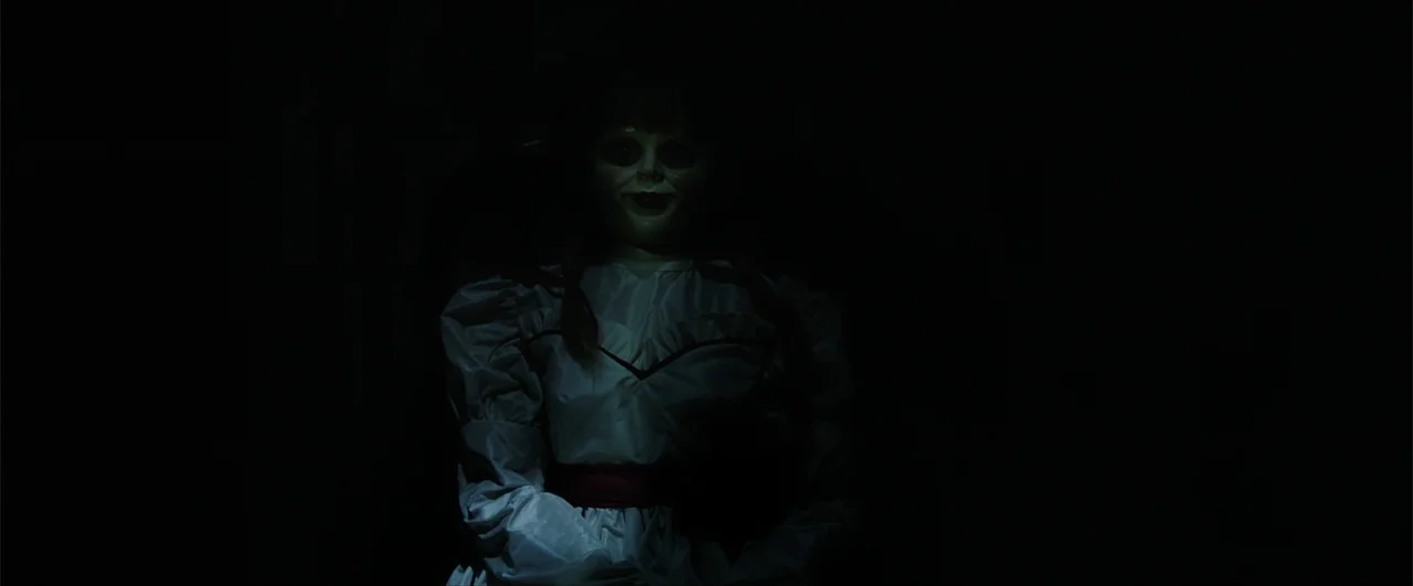 Annabelle: Creation (2017) movie still: medium — An interior space is shrouded in near-total darkness, emphasizing the central figure. A porcelain…