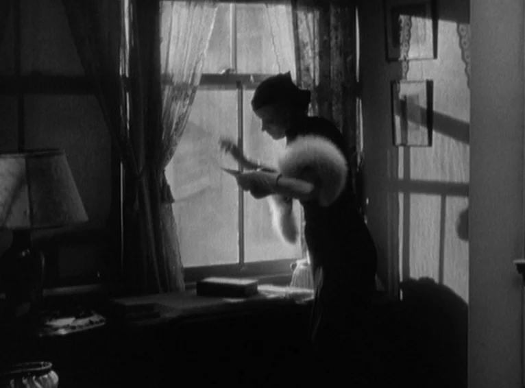 Blonde Venus (1932) movie still: medium — A furnished interior space with a window showing soft daylight streaming through sheer curtains. A woman…