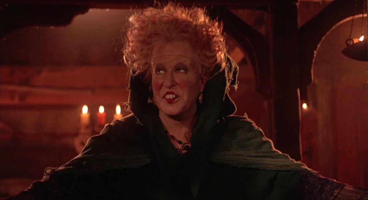 Hocus Pocus (1993) movie still: medium — A dark, wood-paneled room is filled with shadows and lit by flickering candles. An eccentric middle-aged…