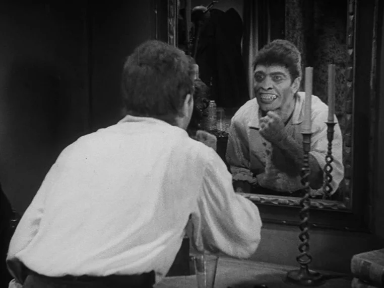 Dr. Jekyll and Mr. Hyde (1931) movie still: medium — A man looks into a vanity mirror while sitting in a dim room. He stares at his own reflection…