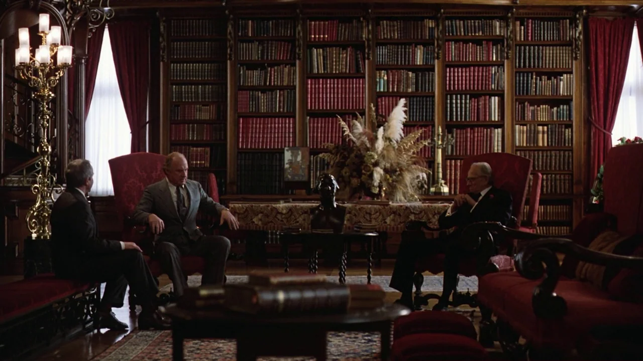 Being There (1979) movie still: wide — A spacious room features floor-to-ceiling wooden bookshelves filled with leather-bound volumes and red…