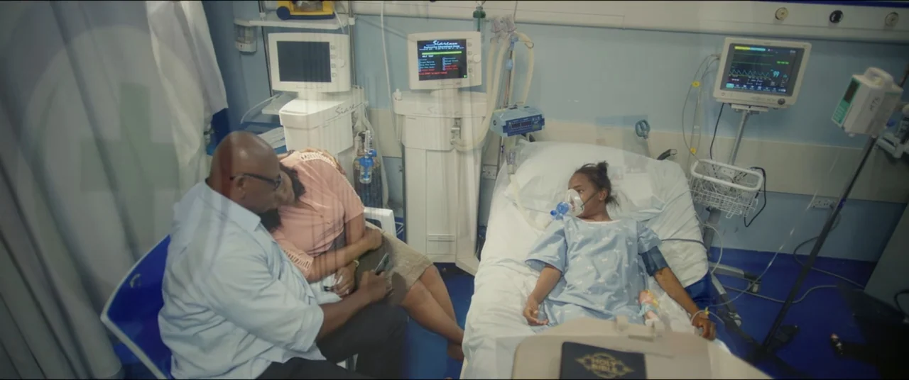 Saving Onome (2024) movie still: medium — A sterile medical room features multiple electronic monitors and white patient bedding. Two people sit…