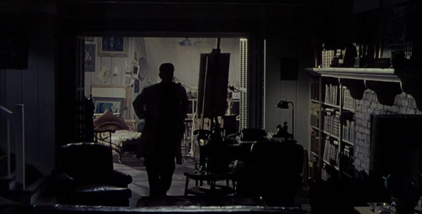 Magnificent Obsession (1954) movie still: medium — A dimly lit room with a fireplace and bookshelves overlooks a brighter adjacent workspace. A man…