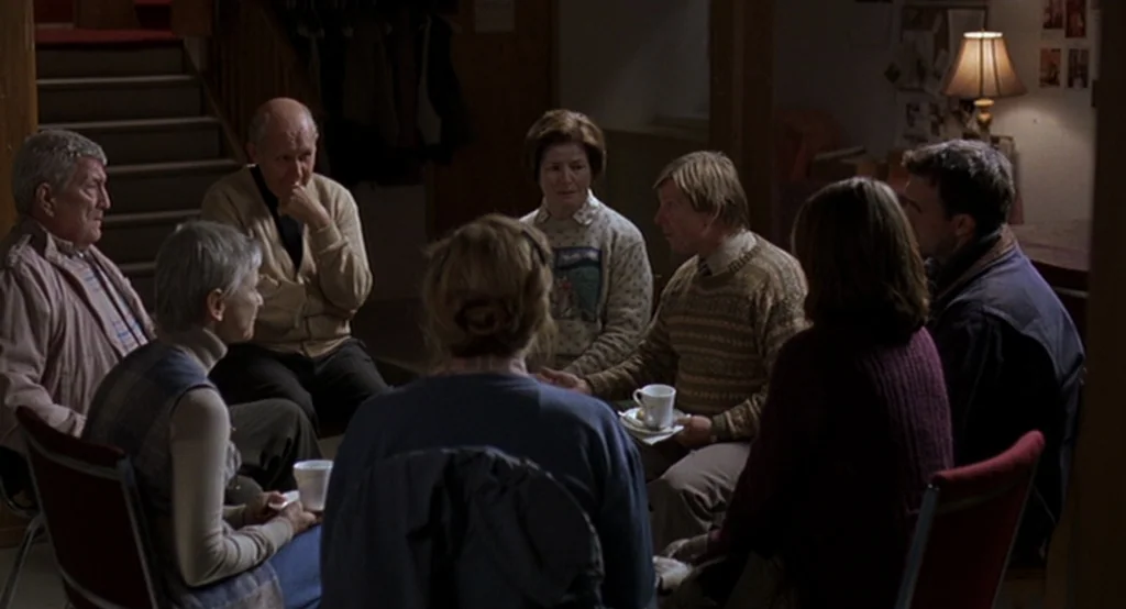 Lars And The Real Girl (2007) movie still: medium — An indoor meeting space features a circle of chairs occupied by several adults. They participate…
