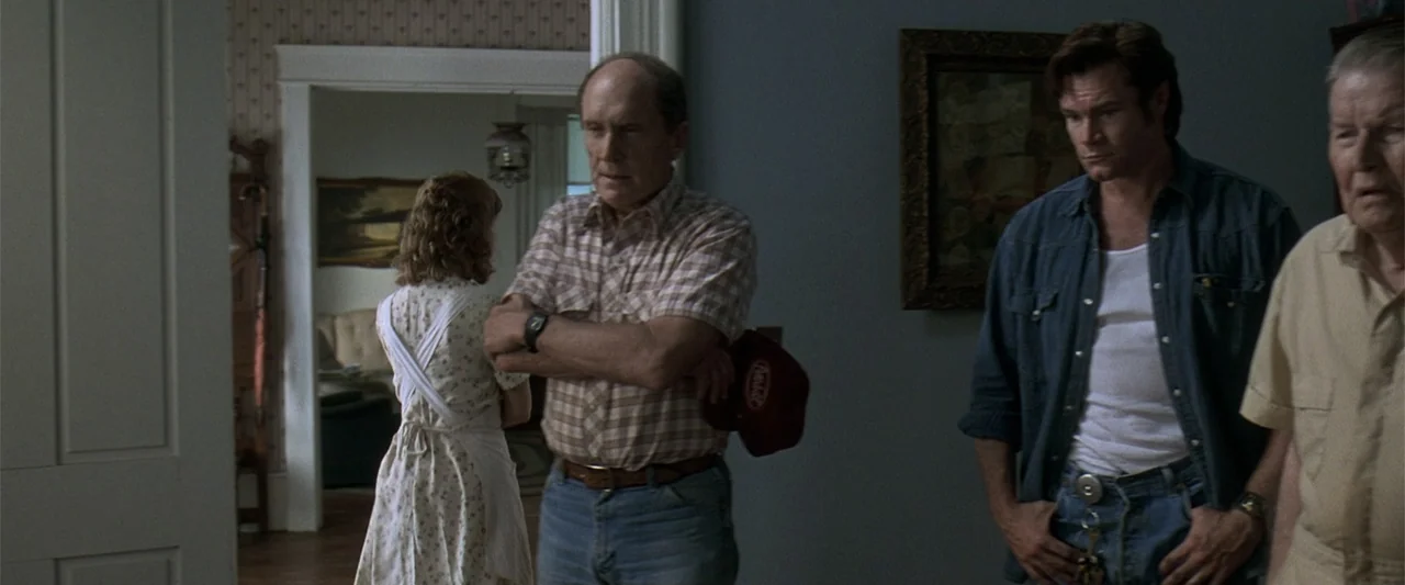 A Family Thing (1996) movie still: medium — An interior hallway in a house with patterned wallpaper and plain painted walls. A mature man and a…