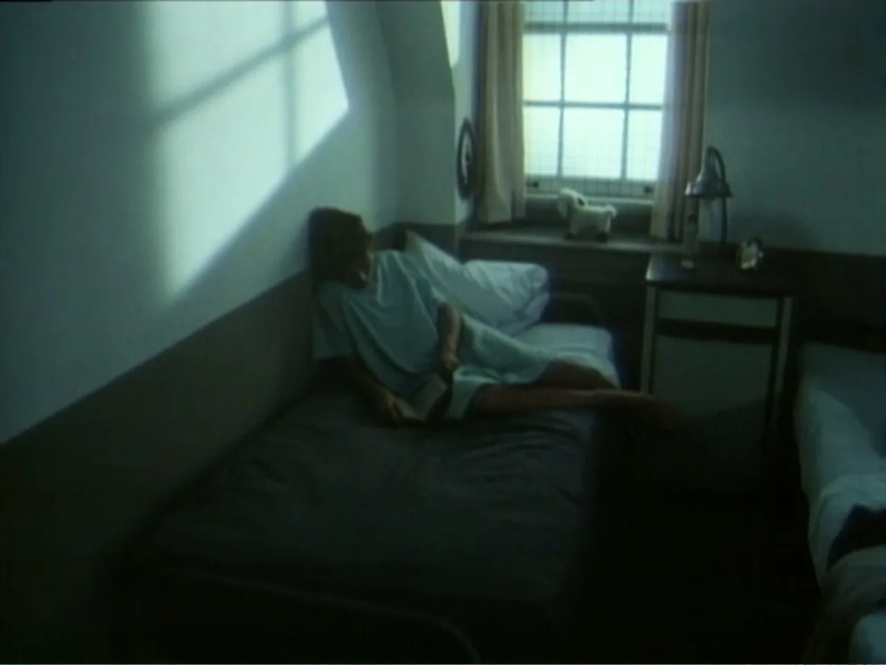 Curtains (1995) movie still: medium — A spare hospital room features a single bed and a small window with curtains. A young patient in a hospital…