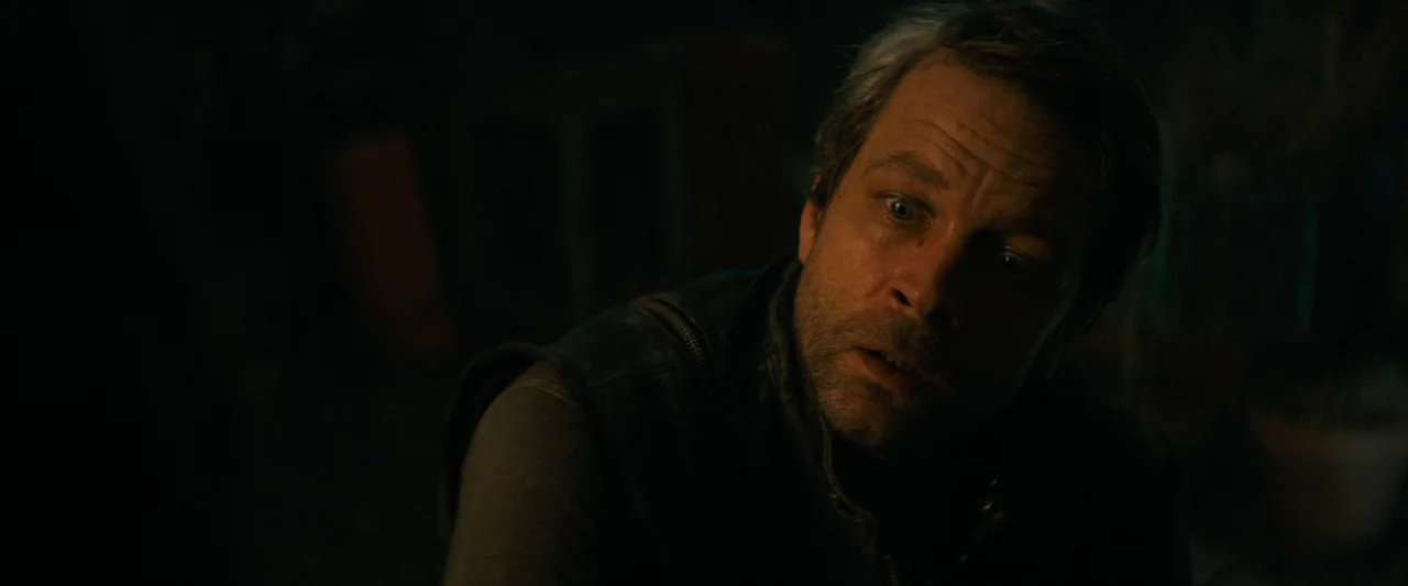 Don’t Breathe 2 (2021) movie still: closeup — The interior space is obscured by heavy darkness with only the subject's face highlighted. A man with…