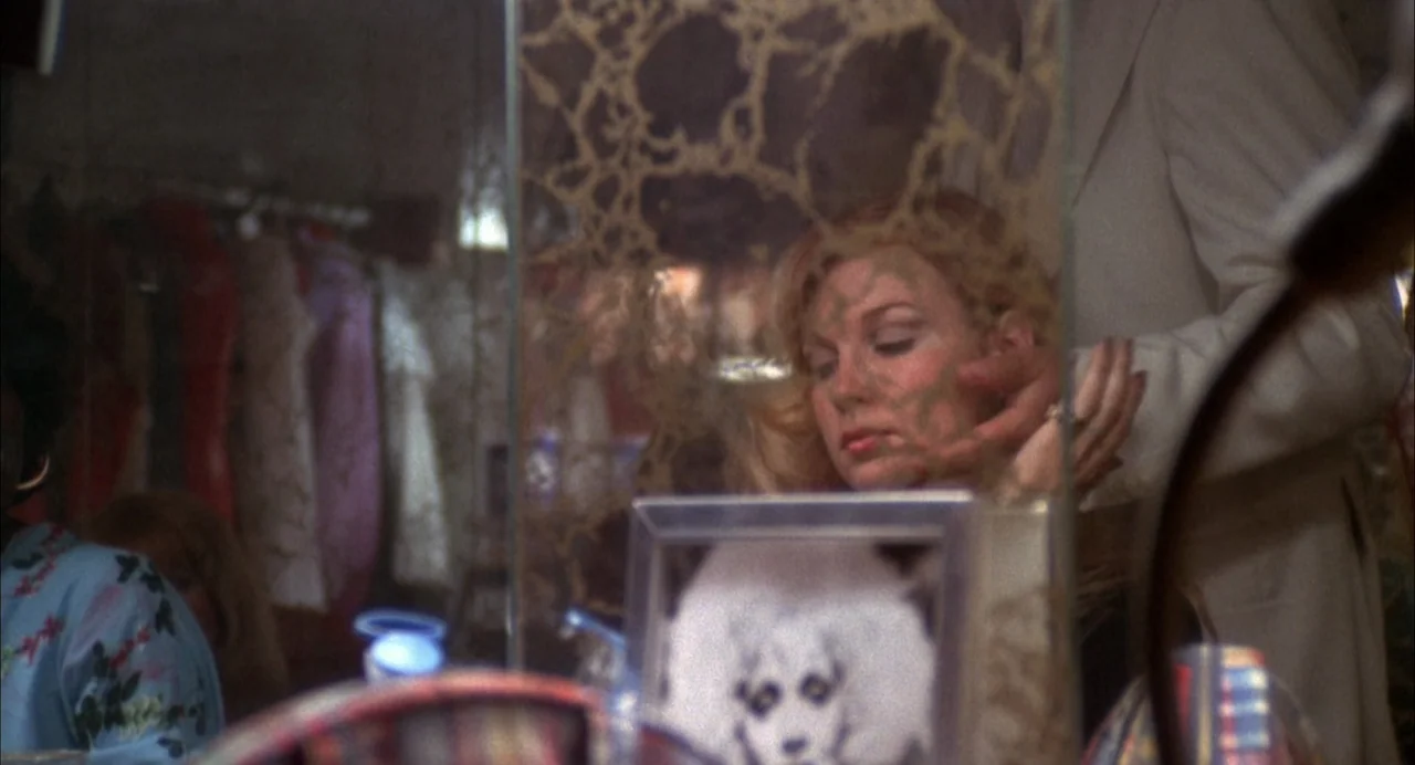 The Killing of a Chinese Bookie (1976) movie still: medium — A dressing room features a vanity with a tarnished, patterned mirror. A woman gazes…
