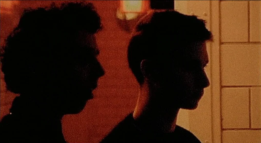 Julien Donkey Boy (1999) movie still: medium — Two individuals stand in silhouette against a wall of light-colored square tiles. A warm light…
