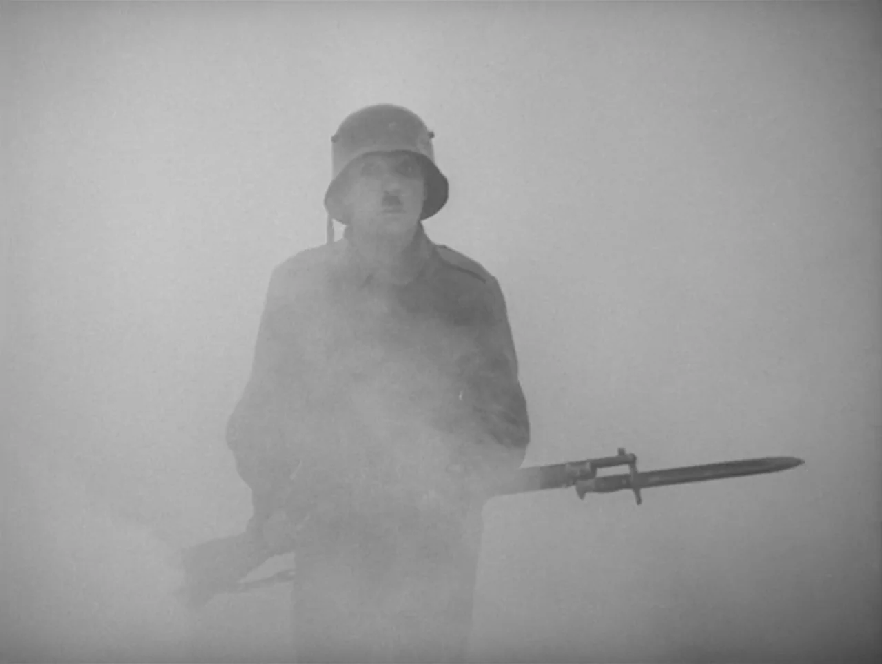 The Great Dictator (1940) movie still: medium — A soldier stands amidst a dense cloud of grey smoke on an obscured battlefield. The man holds a…