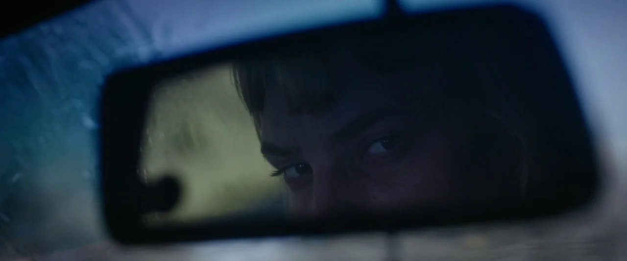 Meanwhile On Earth (2024) movie still: closeup — The view is focused on a rearview mirror inside a motor vehicle. A woman's eyes are visible in the…