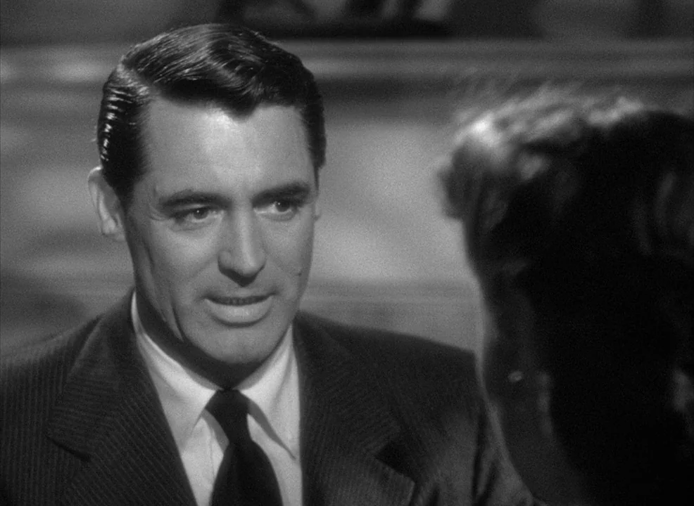 Notorious (1946) movie still: closeup — A man in a suit is seen in a medium closeup during a conversation. He faces slightly off-camera toward…