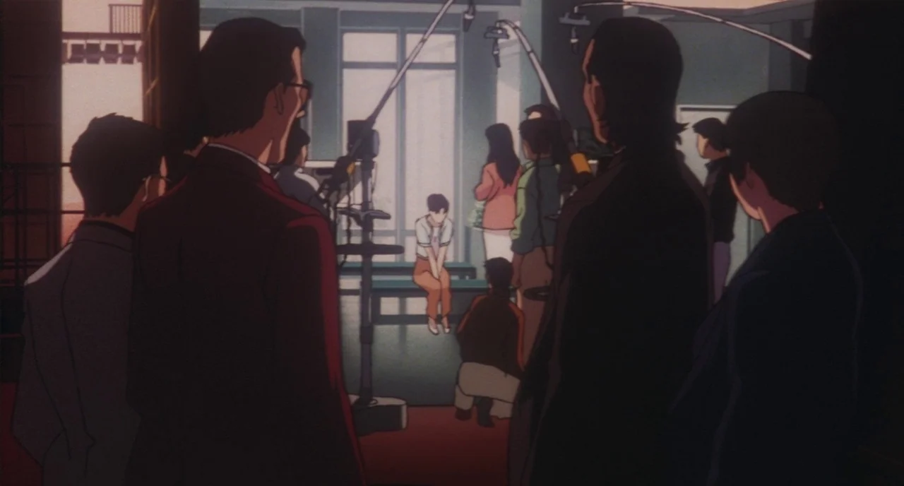 Perfect Blue (1997) movie still: wide — A spacious production room features large windows and visible microphone booms hanging overhead. A group of…