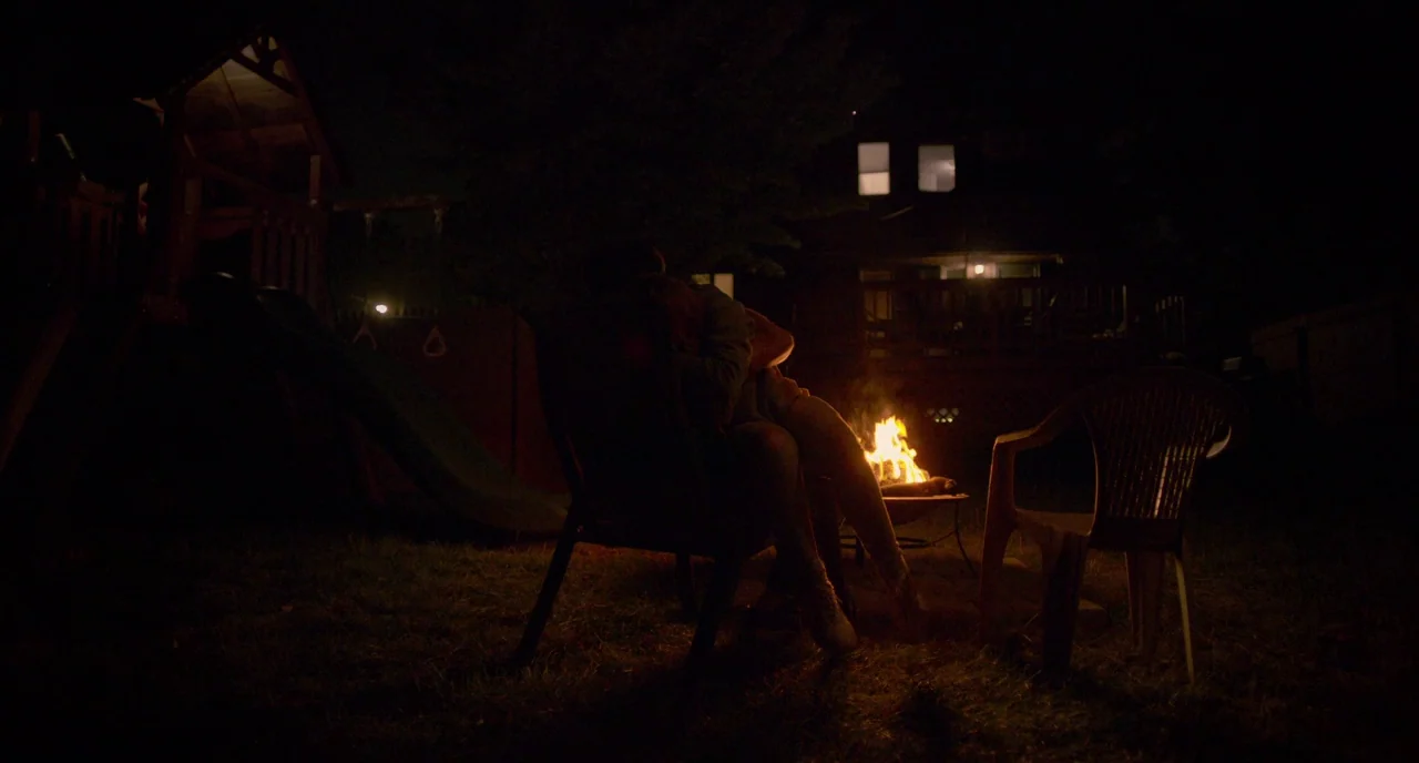 Eighth Grade (2018) movie still: wide — A residential backyard at night features a small metal fire pit burning brightly. Two people are silhouetted…