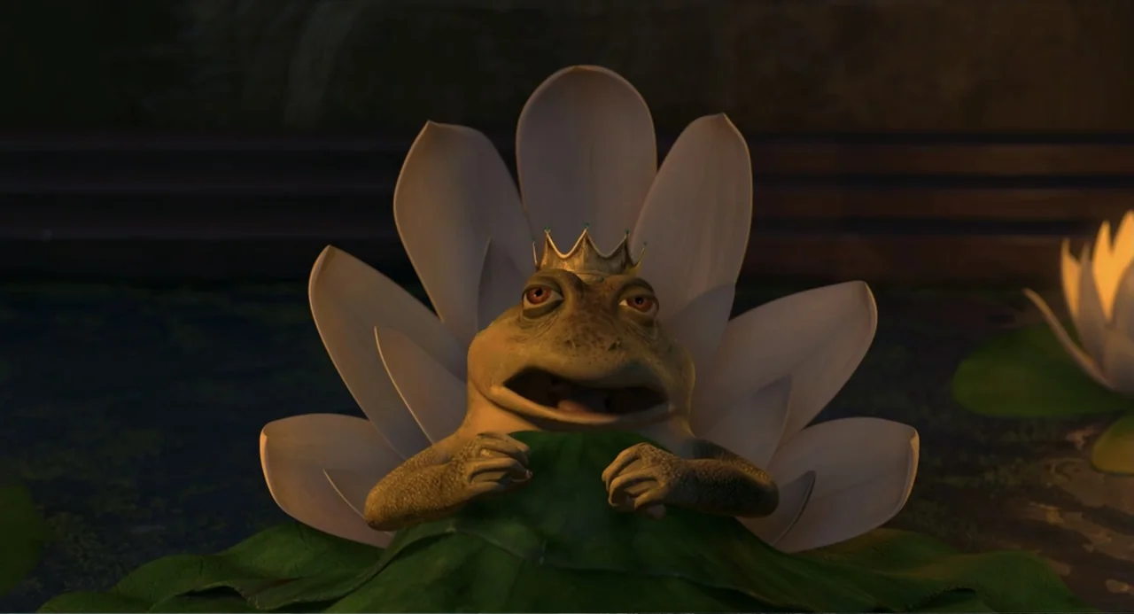 Shrek the Third (2007) movie still: closeup — A dark pond at night features white lotus flowers on the surface. A frog wearing a golden crown rests…