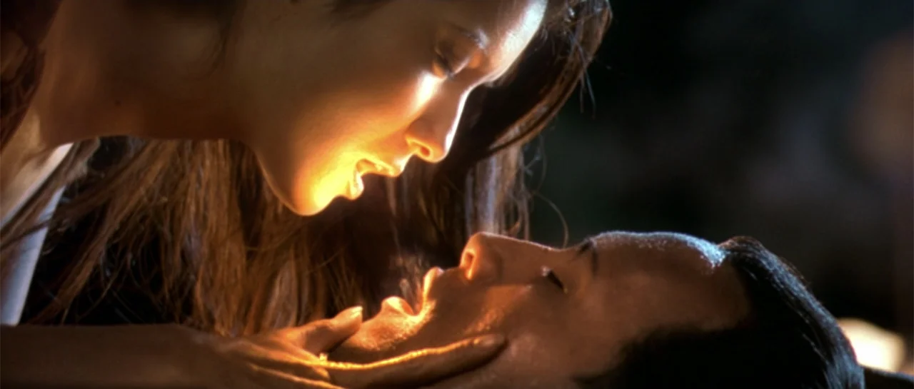 The Scorpion King (2002) movie still: closeup — A dimly lit interior space with a dark background surrounds two individuals close together. A woman…