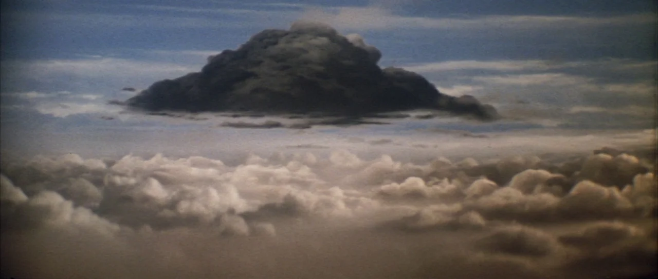 Godzilla Vs Mechagodzilla (1974) movie still: establishing — A vast expanse of sky features a dense, isolated storm cloud floating above. Below it…