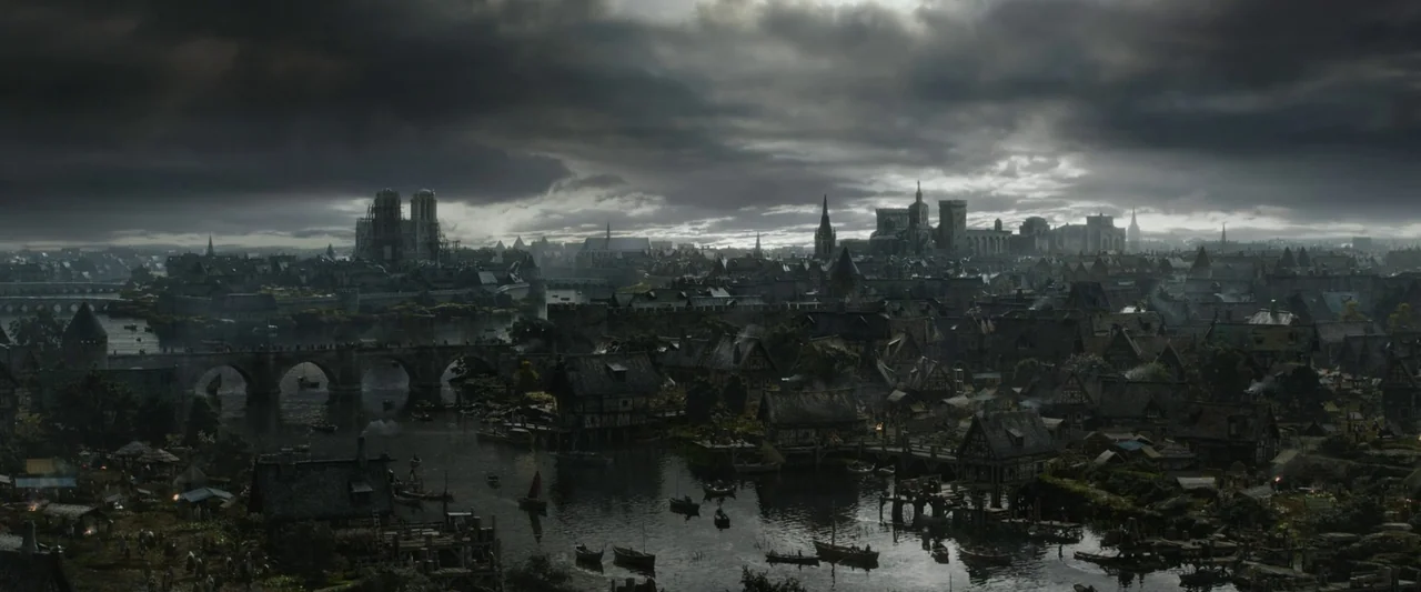 The Last Duel (2021) movie still: establishing — A sprawling medieval city features stone cathedrals, wooden houses, and a river winding through.…