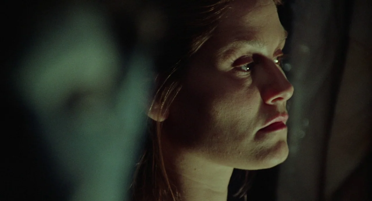 What Happened Was… (1994) movie still: closeup — A dark indoor space where the subject is obscured by low light levels. A woman looks off-screen,…