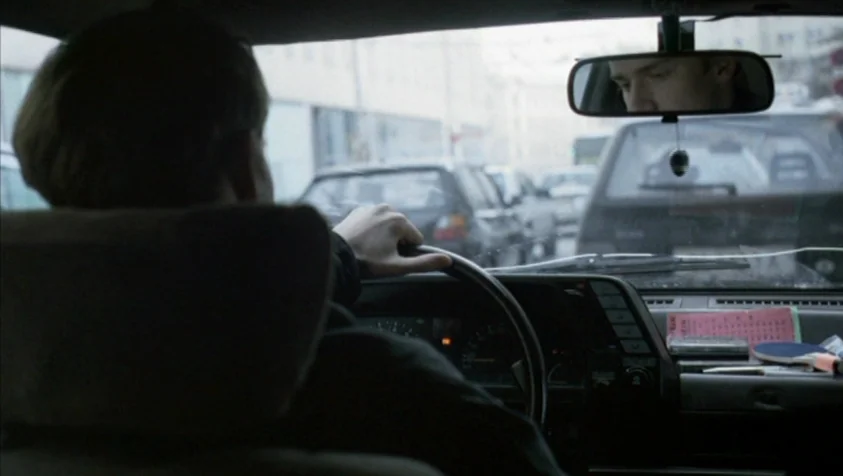 71 Fragments of a Chronology of Chance (1994) movie still: medium — A view from behind the driver of a car navigating a city street. The driver…