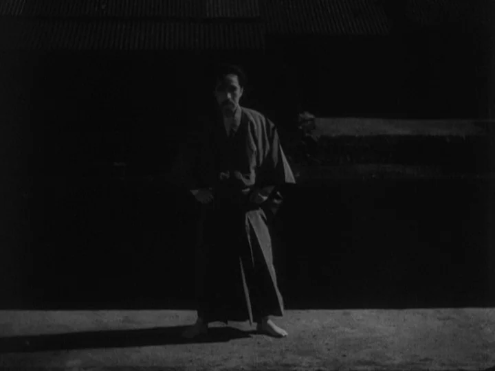 Sanshiro Sugata (1943) movie still: fullbody — A dark outdoor space with a smooth concrete floor at night. A man dressed in traditional clothing…