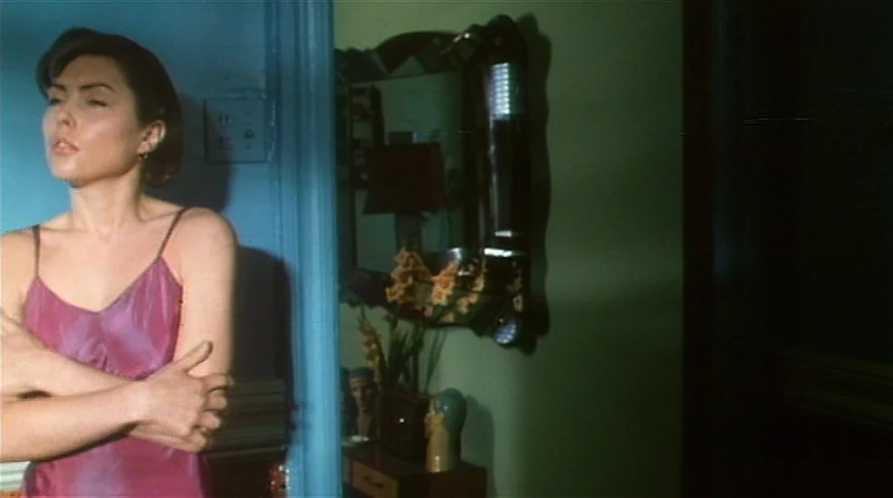 Union City (1980) movie still: medium — A woman stands in a doorway between a blue room and a green room. She is positioned against the blue wall…