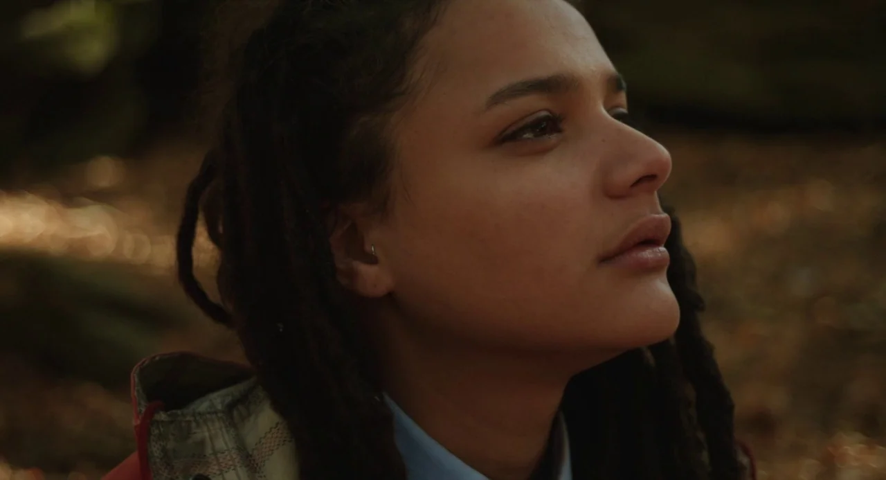 The Miseducation of Cameron Post (2018) movie still: closeup — A woodland environment features a blurred background of dried fallen leaves and…
