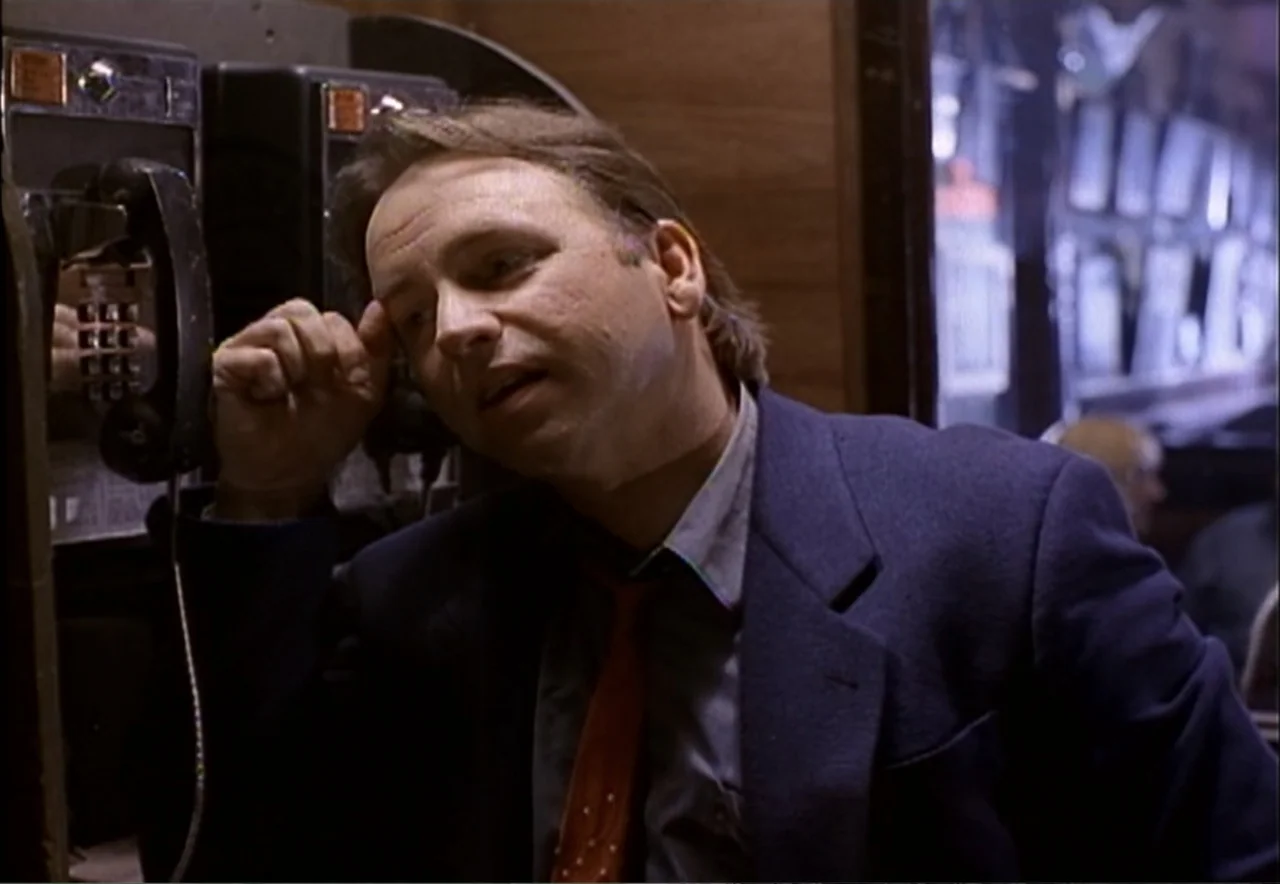 Chance of a Lifetime (1998) movie still: medium — A dimly lit phone booth features wood paneled walls and a classic payphone unit. A middle-aged man…