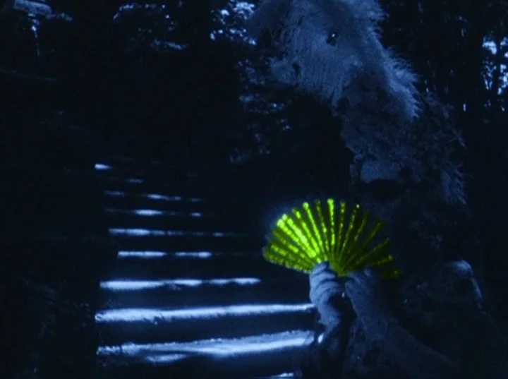Eaux d’Artifice (1953) movie still: medium — A dark outdoor staircase is illuminated by sharp blue light strips on the treads. A figure in a…