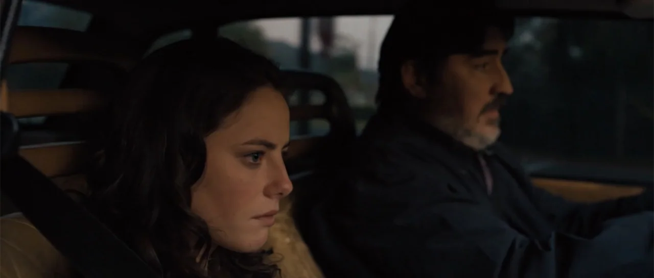 The Truth About Emanuel (2013) movie still: medium — The interior of a moving car at dusk shows a driver and passenger. The passenger stares forward…