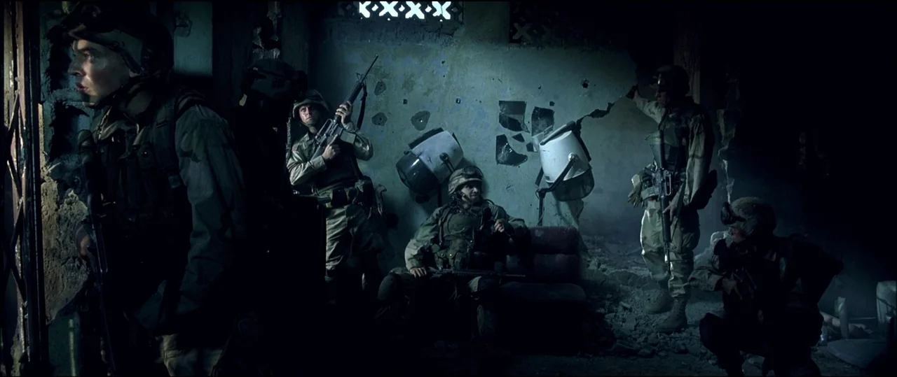 Black Hawk Down (2001) movie still: wide — A war-torn interior of a hair salon with broken walls and debris on floor. Several soldiers stand and sit…