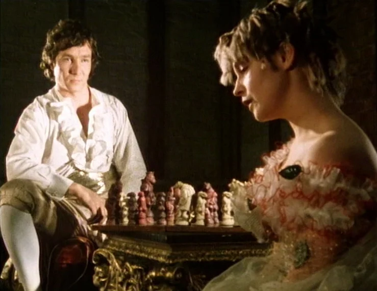 The Tempest (1979) movie still: medium — A dark, wood-paneled room features a central ornate pedestal table holding a chessboard. A man in a period…