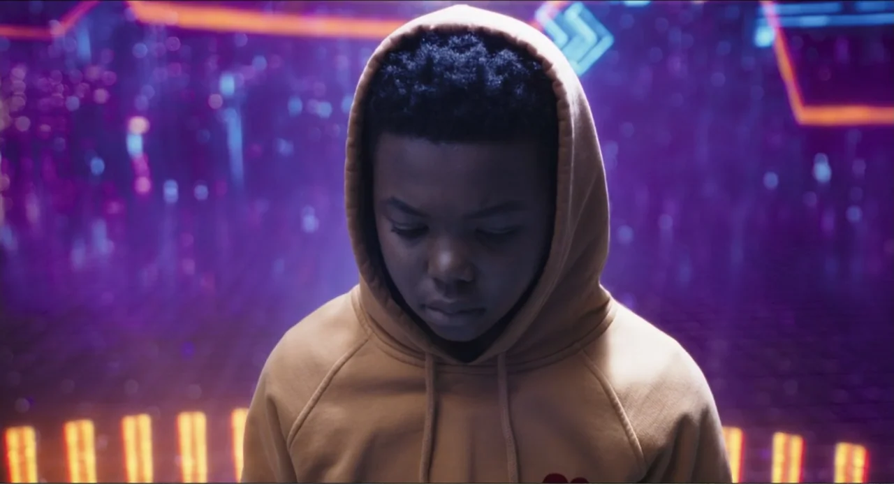 Space Jam: A New Legacy (2021) movie still: medium — A person stands in a dimly lit space with blurry, glowing neon light patterns behind. The…