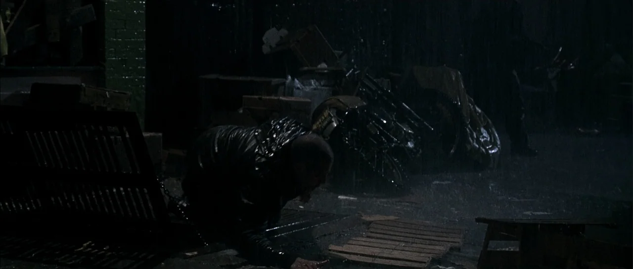 A Man Apart (2003) movie still: medium — A dark, rain-slicked alleyway is cluttered with discarded wooden debris and metal wreckage. A lone man…