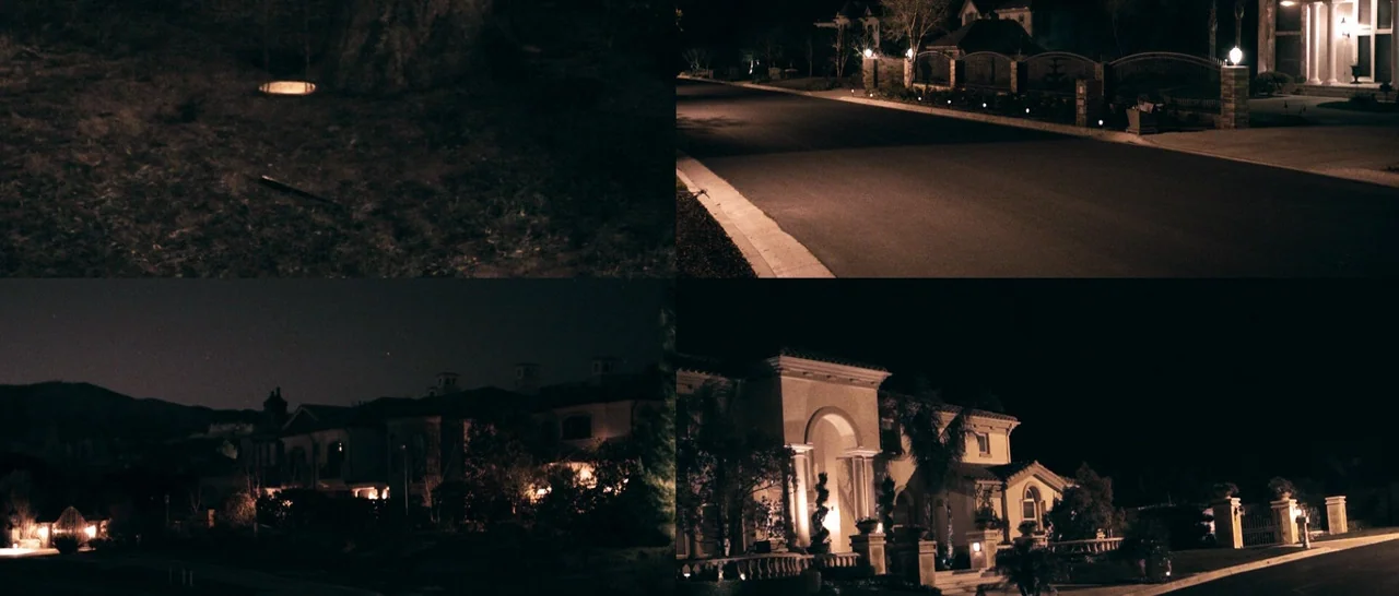 The Purge (2013) movie still: establishing — A quiet residential street at night features large houses with warm exterior porch lights. The suburban…