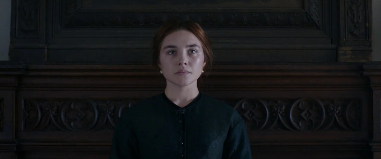 Lady Macbeth (2016) movie still: medium — A dark wooden wall with ornate carved wood paneling serves as the backdrop. A woman in a high-collared…