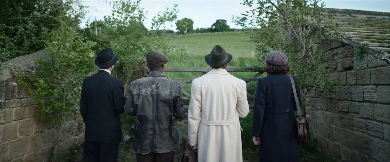 Nandor Fodor and the Talking Mongoose (2023) movie still: fullbody — A rural landscape features a stone wall and a wooden gate leading to fields.…