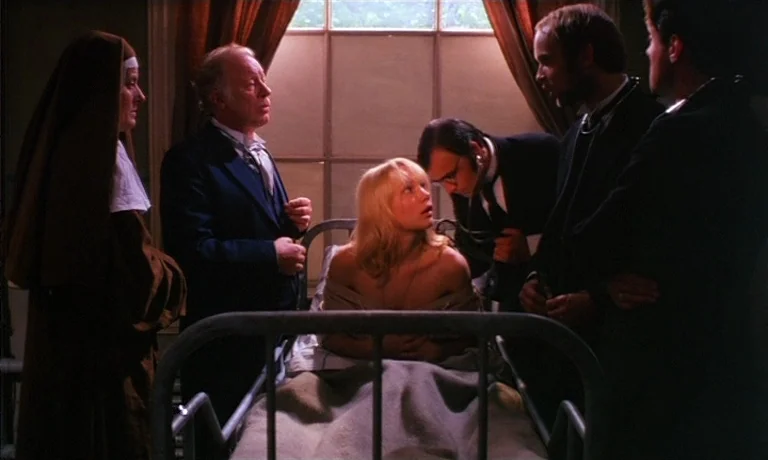 Katie Tippel (1975) movie still: medium — A dimly lit room contains a white metal hospital bed centered before a large window. A patient sits…