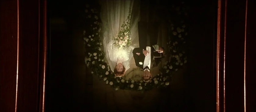 The House of Mirth (2000) movie still: fullbody — An upside-down framed photograph shows a bride and groom standing before a floral arch. The couple…