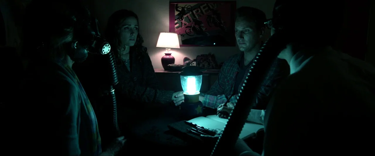 Insidious (2010) movie still: medium — A dimly lit room at night containing a group of people sitting around a table. They are gathered in a circle…