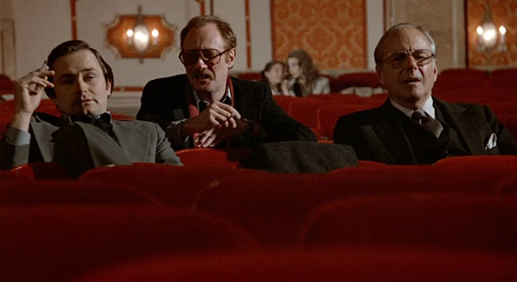 All That Jazz (1979) movie still: medium — An ornate cinema features rows of red velvet seats and wall sconces. Three middle-aged men sit together…