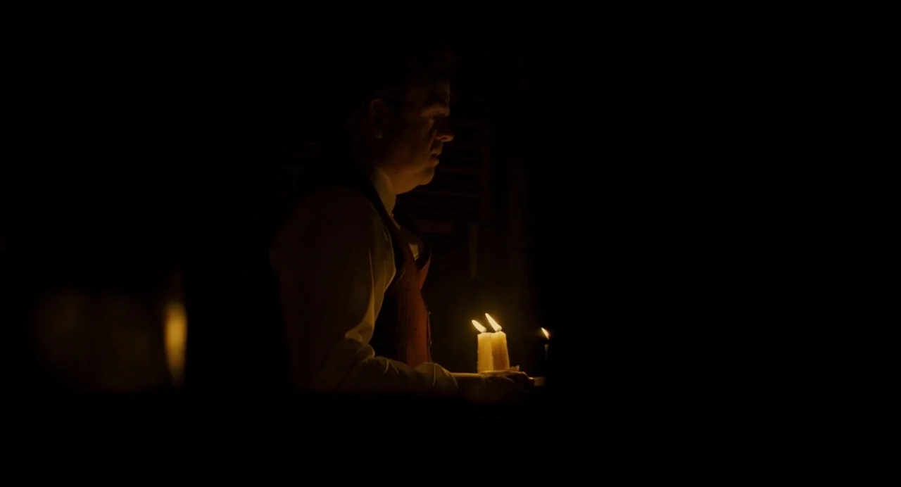 Berberian Sound Studio (2012) movie still: medium — A dark, unlit room with minimal interior architectural detail visible. An older man in a…