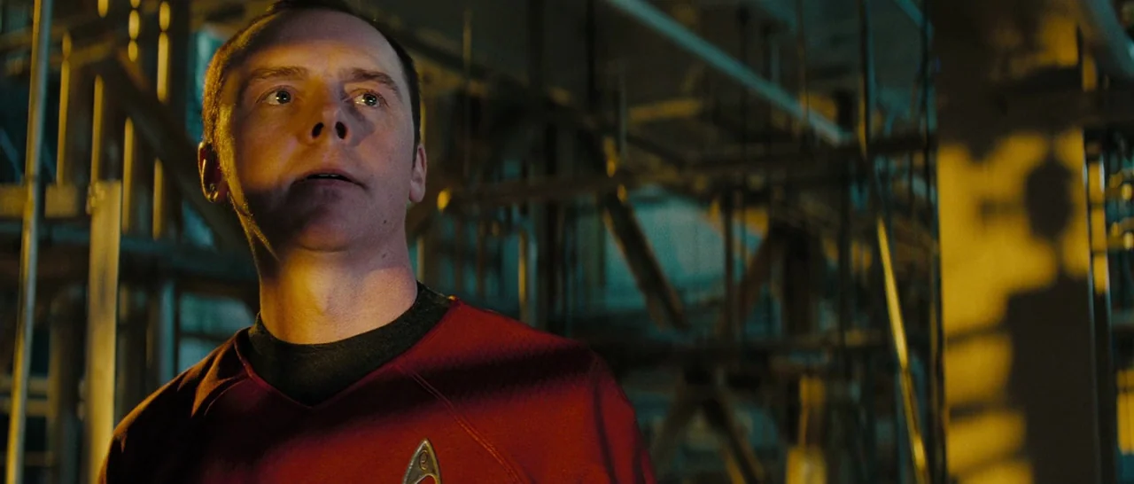 Star Trek (2009) movie still: medium — An industrial space filled with metal pipes and machinery is illuminated by amber lighting. A man wearing a…