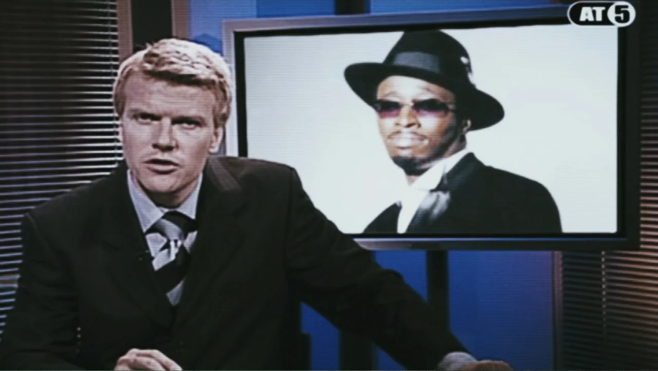 Deuce Bigalow: European Gigolo (2005) movie still: medium — A television news studio features a male anchor standing before a monitor screen. The…