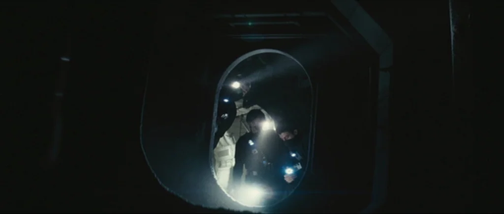 Sunshine movie still: medium — A dark, cramped industrial tunnel with octagonal framing and metallic surfaces. Three figures in tactical gear…