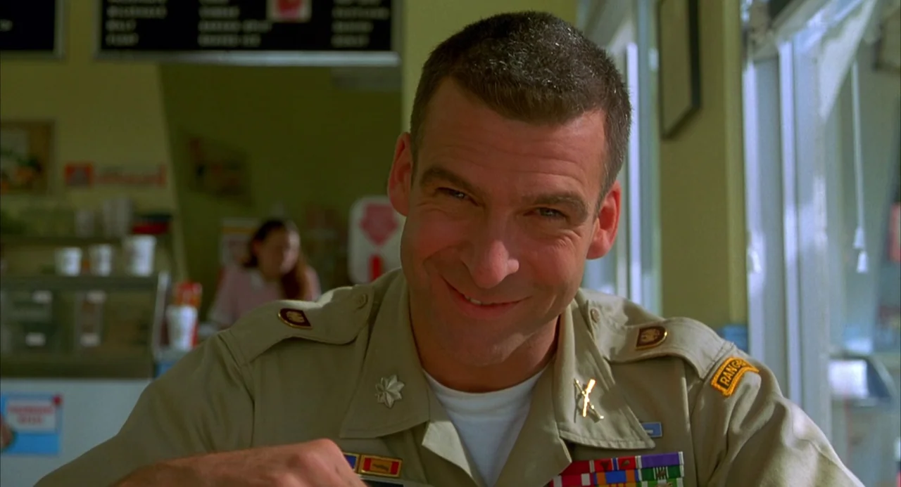 Hulk (2003) movie still: closeup — A man in a military uniform sits at a table inside a casual eatery. He looks directly toward the camera with a…