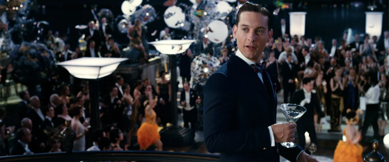 The Great Gatsby (2013) movie still: medium — A crowded, lavish 1920s ballroom features numerous guests in formal evening attire amidst elaborate…