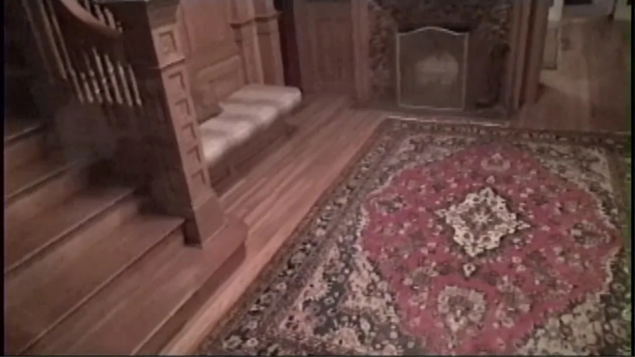 S-V/H/S: Un cortometraje de Las Crónicas del Miedo (2023) movie still: establishing — A traditional wood-paneled residential foyer features a…
