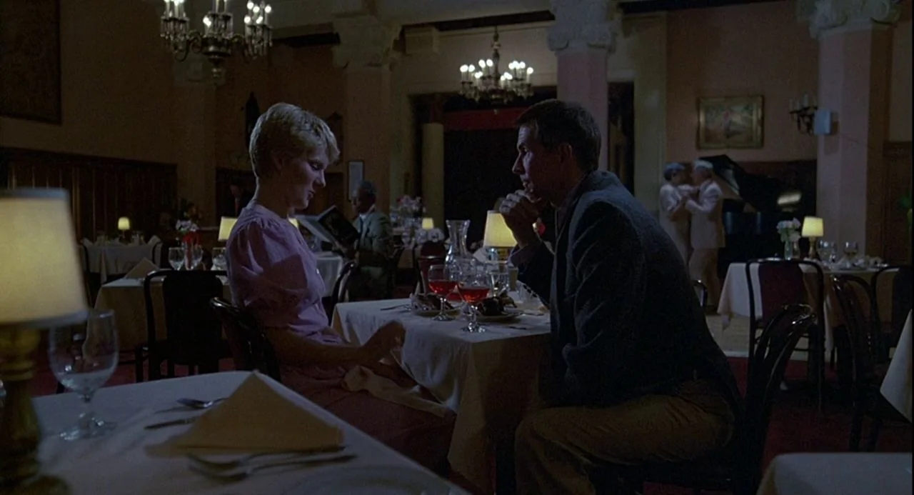 Psycho III (1986) movie still: medium — An upscale dining room features white tablecloths and dark wooden wall paneling with dim lighting. A couple…